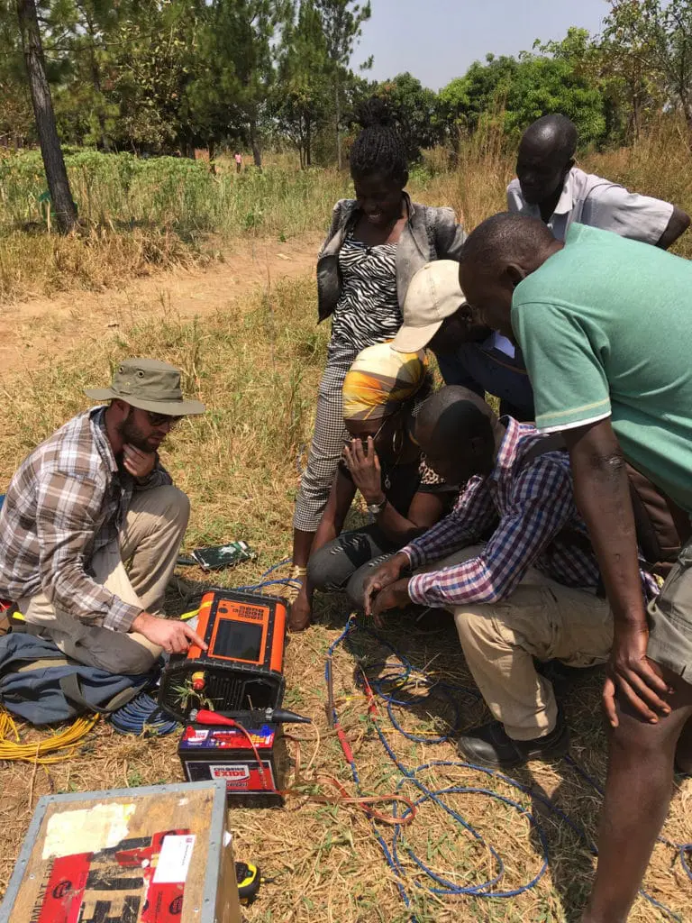   Max Layton, Geophysicist at Advisian, is teaching a few students - Proscovia, Lucy, Francis and Patrick - along with heads of the village about our resistivity survey.     Read Journal #3   