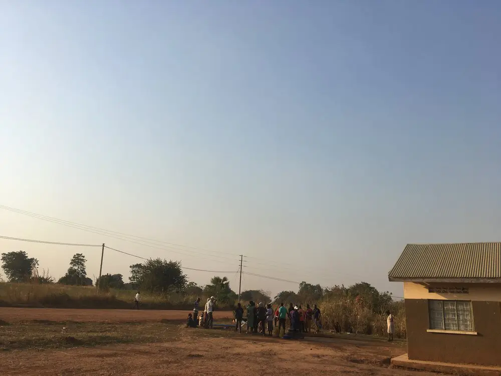  A group of students repairing a well, with the clinic building in the foreground 