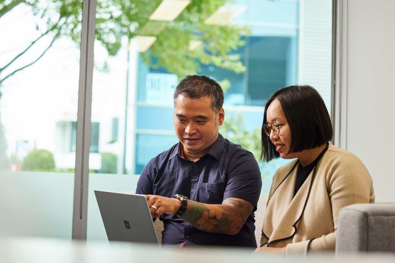 A photograph of two people looking and pointing at a screen