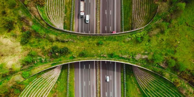 Aerial view by drone of the Ecoduct De Borkeld for the wildlife, crossing above multiple highway with bicycle lane bridge and people commuting in the green Netherlands during springtime. GettyImages-1488179335