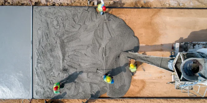 A construction worker pouring a wet concrete at road construction site. GettyImages-1186331518