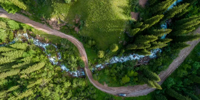 Pine forest from above, spring season, forest road and river. Shutterstock 1172089639