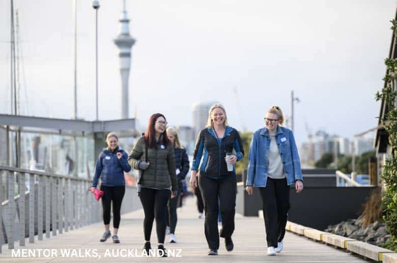 A photograph of 5 women walking on a path with a city in the background captioned Mentor Walks, Auckland NZ