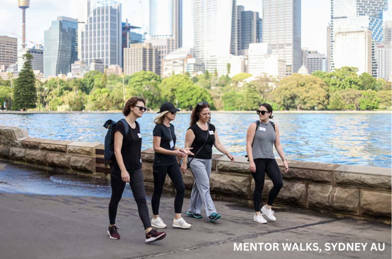 A photograph of 4 women walking on a path alongside a river with a city in the background captioned Mentor Walks, Sydney AU