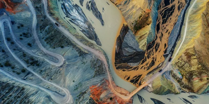 Mining truck driving down winding dirt road to the bottom of a canyon. GettyImages-1174828157