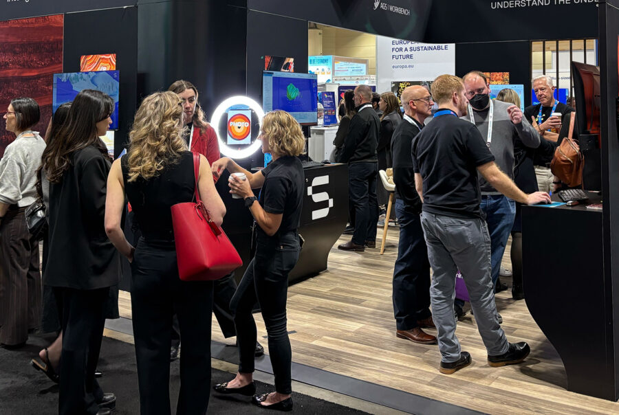 Scene from the PDAC mineral exploration and mining convention showing a crowd of industry professionals. A banner for the PDAC event in Toronto is prominently displayed in the background.