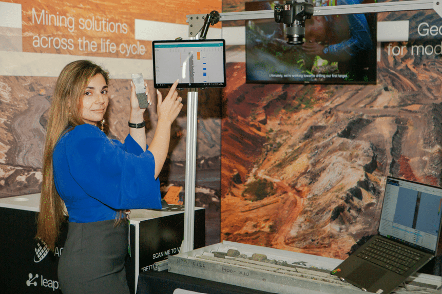 A photograph of Elisenda Rodriguez Perez in a Seequent conference booth pointing to an Imago demonstration setup