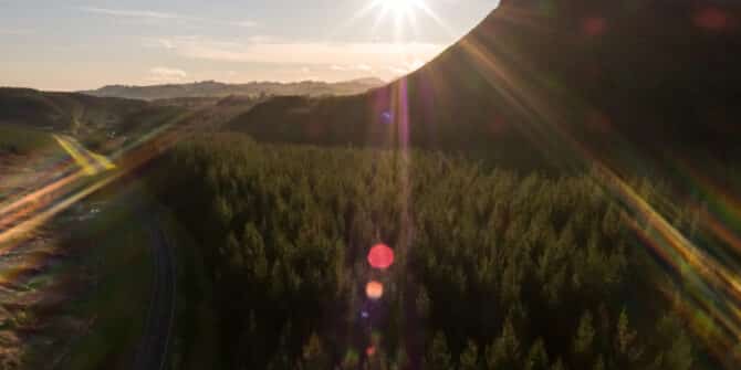 A photo of a sunset over a rocky, forested landscape