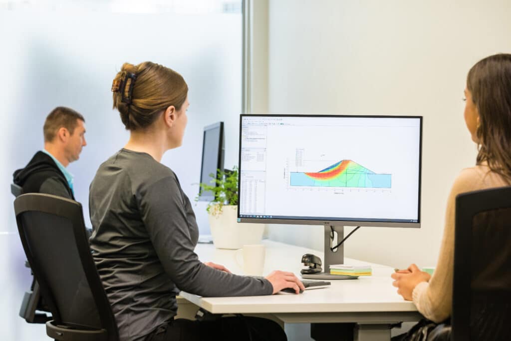 A photograph of two women working at a screen with a model from Seequent's Geostudio SEEP/W visible on screen.