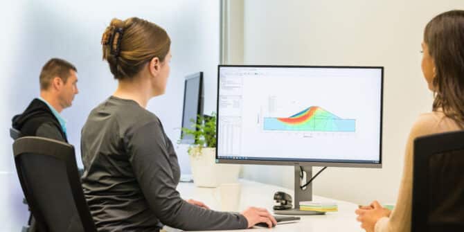 A photograph of two women working at a screen with a model from Seequent's Geostudio SEEP/W visible on screen.