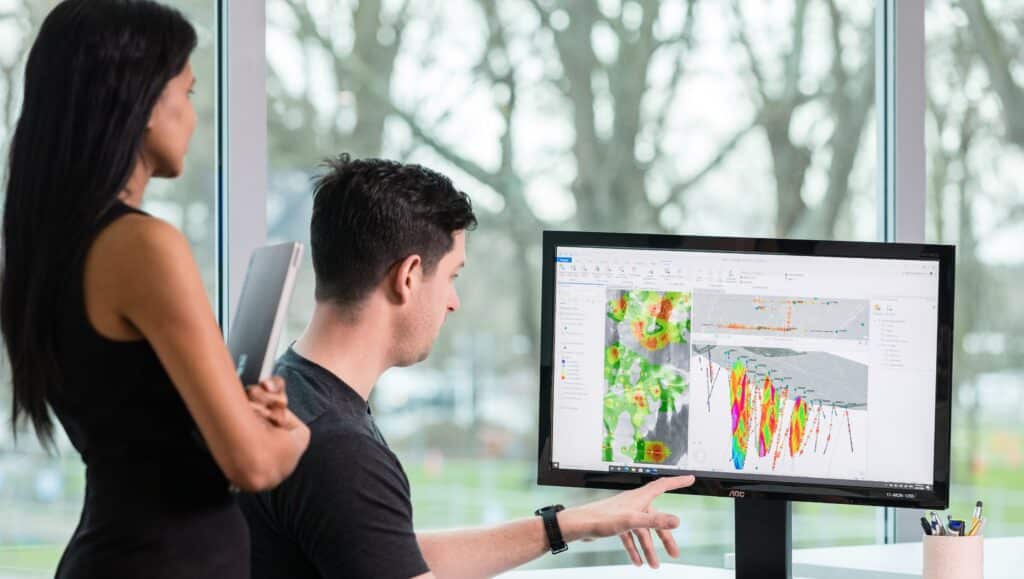 A photograph of a man and a woman looking at a screen where Target for ArcGIS pro is being used to 3D model geological data