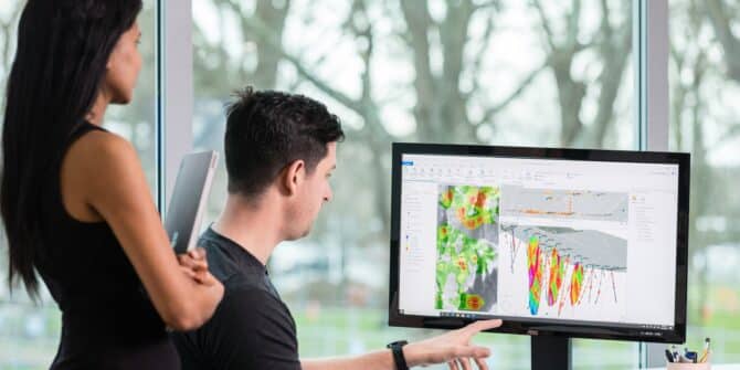 A photograph of a man and a woman looking at a screen where Target for ArcGIS pro is being used to 3D model geological data