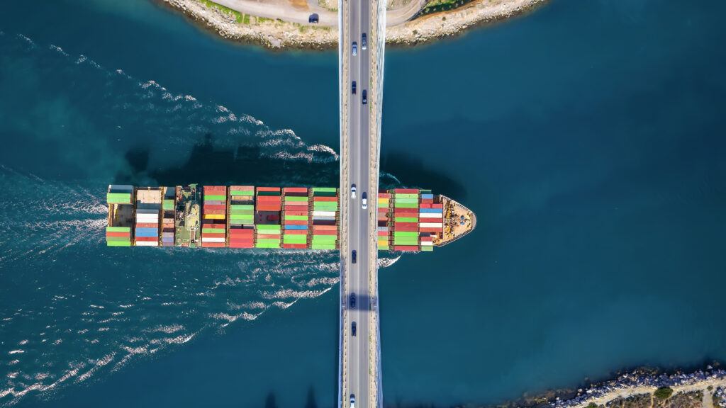 A cargo ship passing under a bridge