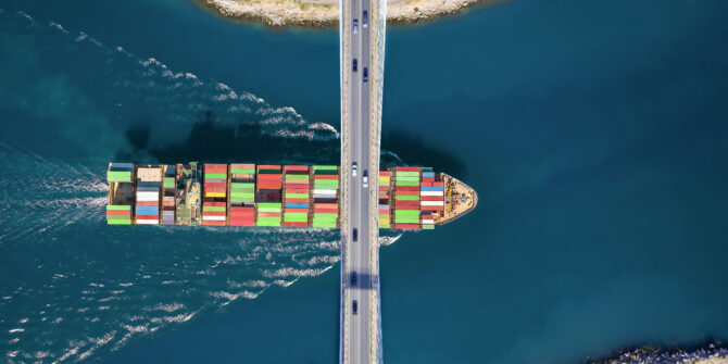 A cargo ship passing under a bridge
