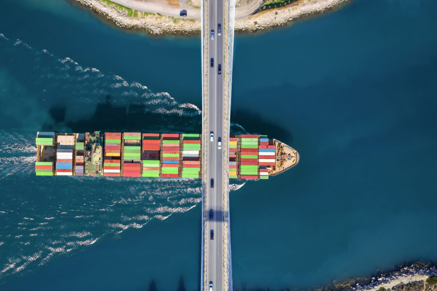 A cargo ship passing under a bridge