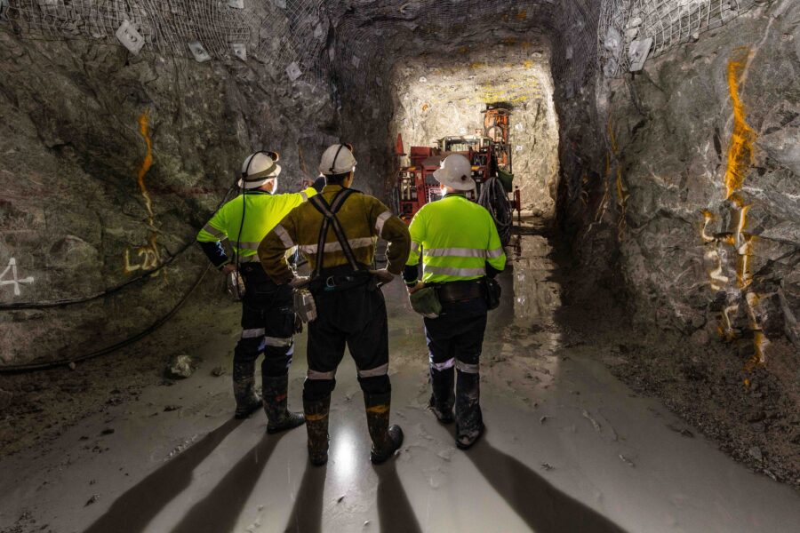 Miners in a tunnel inspecting a rock face.
