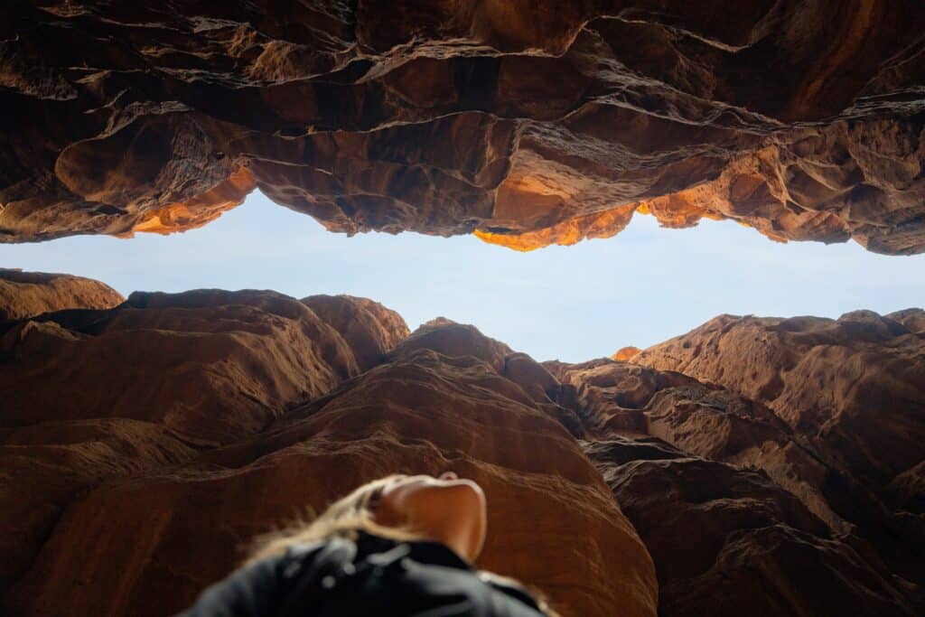 A photo of a woman looking up through a canyon