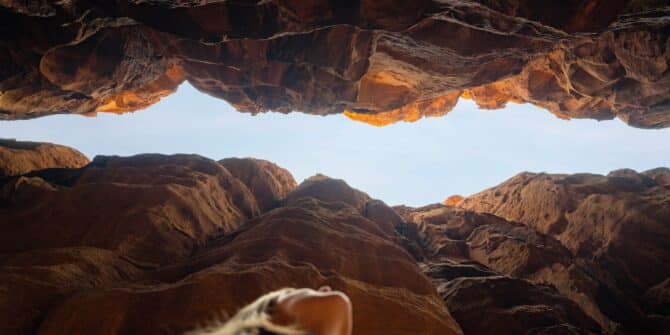 A photo of a woman looking up through a canyon