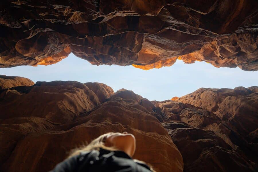 A photo of a woman looking up through a canyon