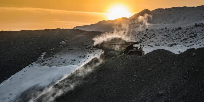 A photo of a mining truck set against slopes and a sunset.