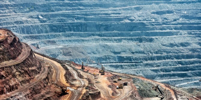 close up of quarry extracting iron ore with heavy trucks, excavators, diggers and locomotives